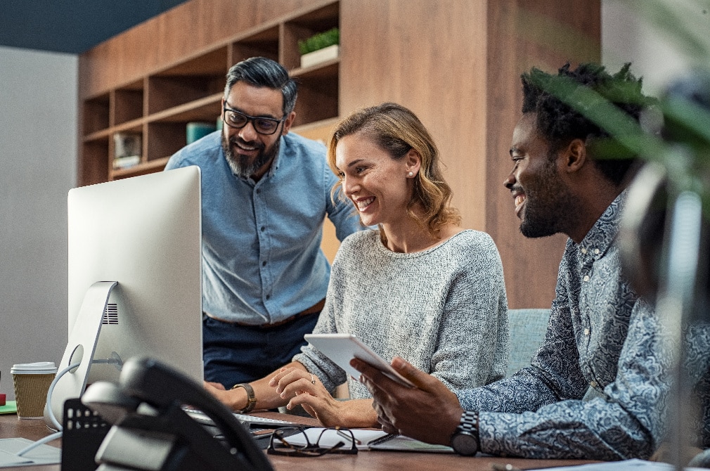 three people looking at a screen collaborating