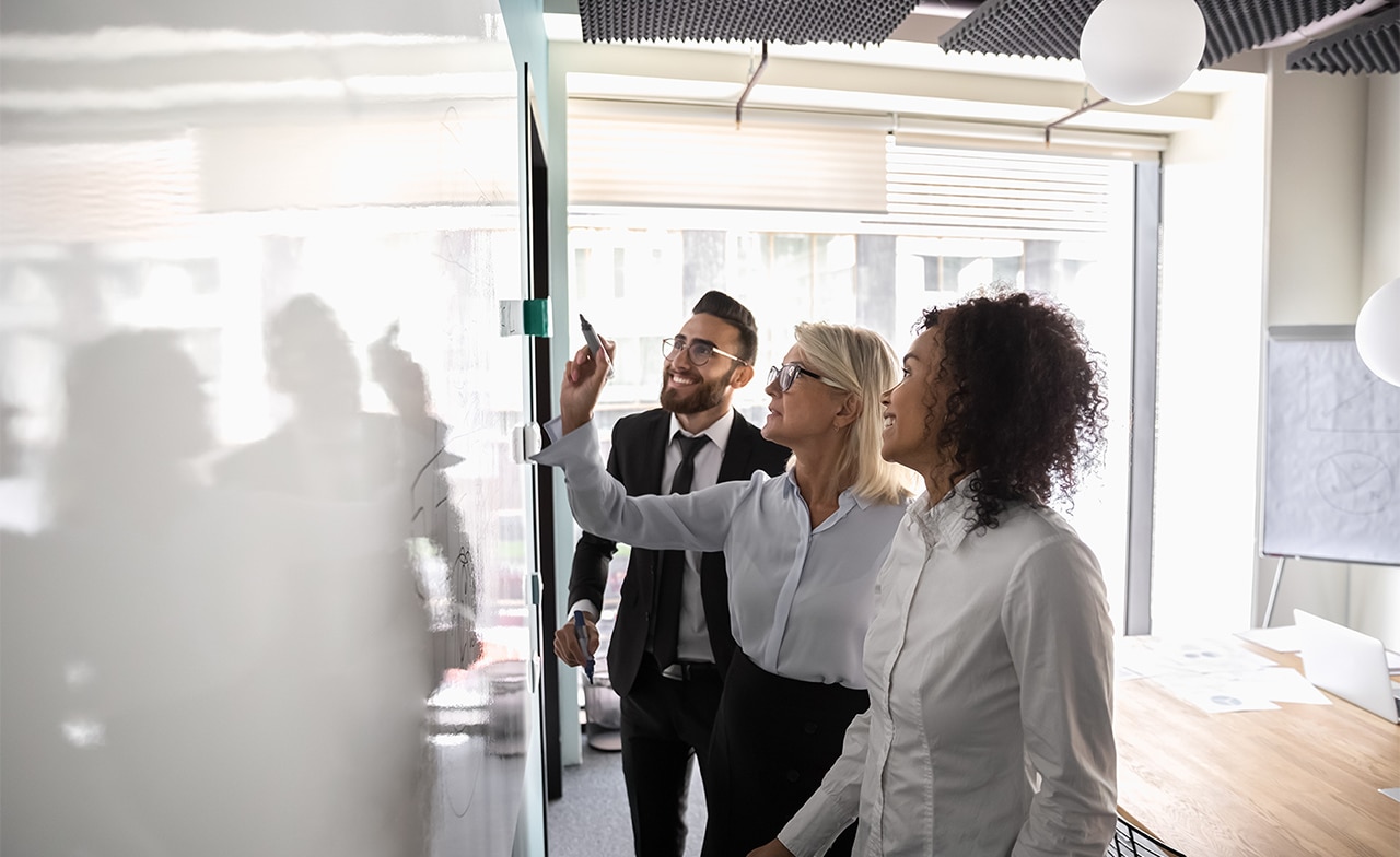 team members collaborating in front of a white board