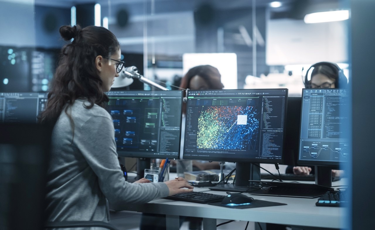 engineer looking at data on multiple computers in a technical environment