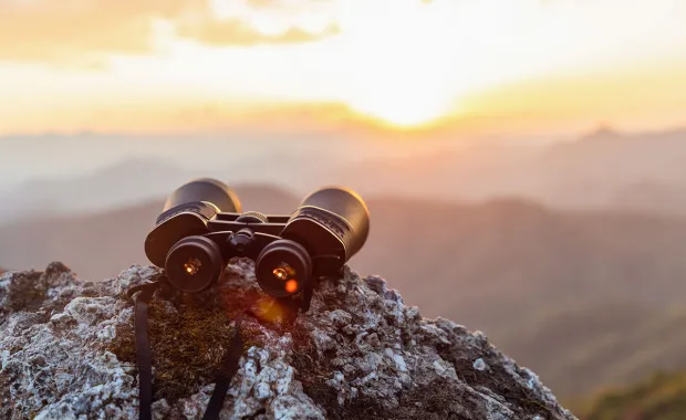 Binoculars on a rock overlooking mountains