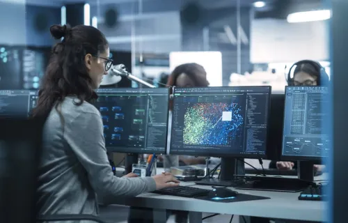 engineer looking at data on multiple computers in a technical environment