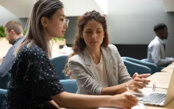 two people speaking in front of laptop