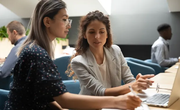 two people speaking in front of laptop